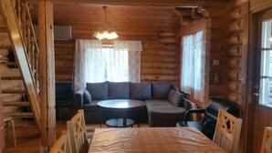 A log cabin interior with a sofa set, a dining table, and a staircase. - Raikala (Savonlinna)