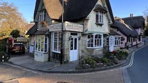 Il s’agit d’un bâtiment traditionnel doté d’un toit de chaume, appelé « Pencil Cottage ». Il se distingue par sa façade en pierre, ses nombreuses fenêtres et une enseigne.