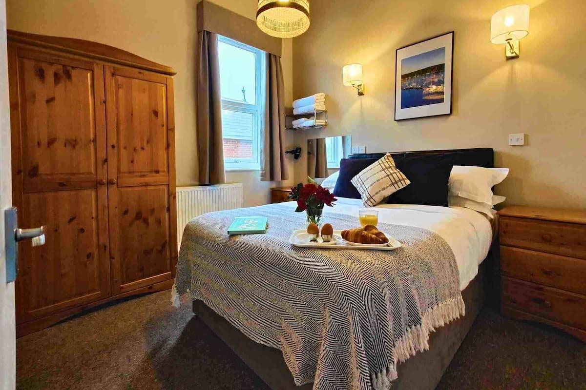 Una camera da letto con un letto, un armadio in legno, una finestra e un quadro appeso al muro.