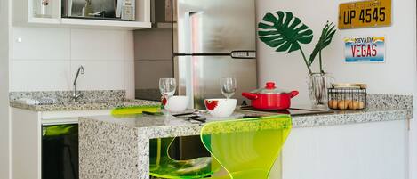 Una cocina moderna con una isla central, electrodomésticos de acero inoxidable y un armario superior de color amarillo brillante.