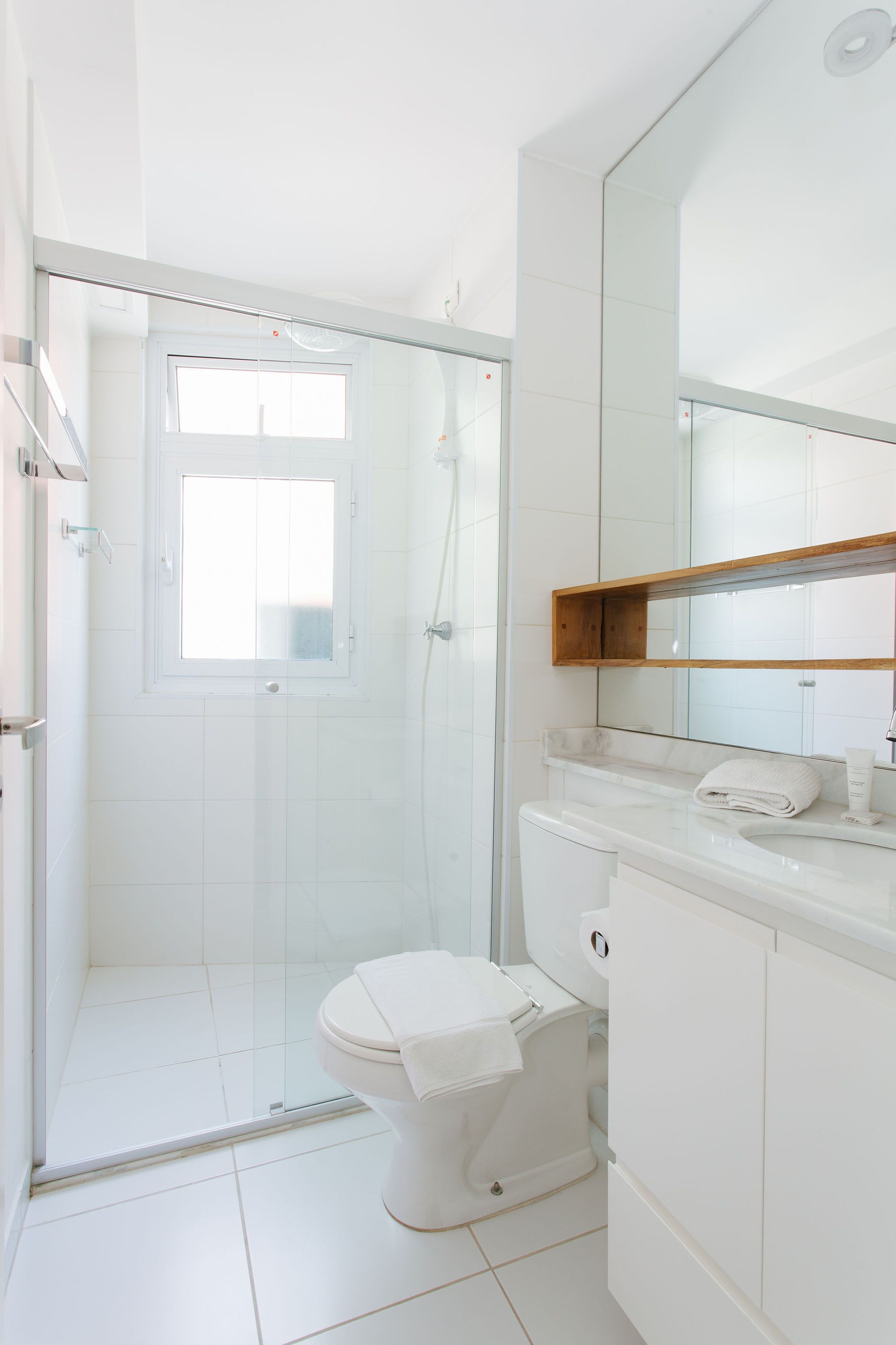 A modern bathroom with a glass-enclosed shower, a toilet, and a vanity with a mirror.