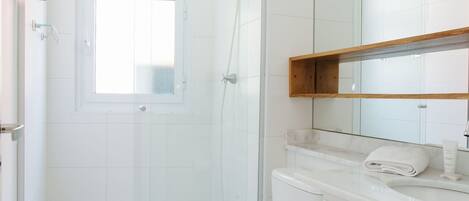 A modern bathroom with a glass-enclosed shower, a toilet, and a vanity with a mirror.