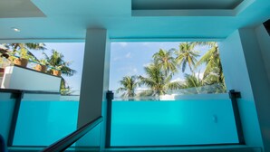 A modern hotel room with a large window overlooking palm trees and a clear sky. - Signature Boracay Blue (Boracay Island)
