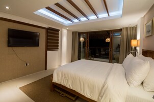 A modern hotel room with a large bed, a flat-screen TV mounted on the wall, and a skylight above the bed.