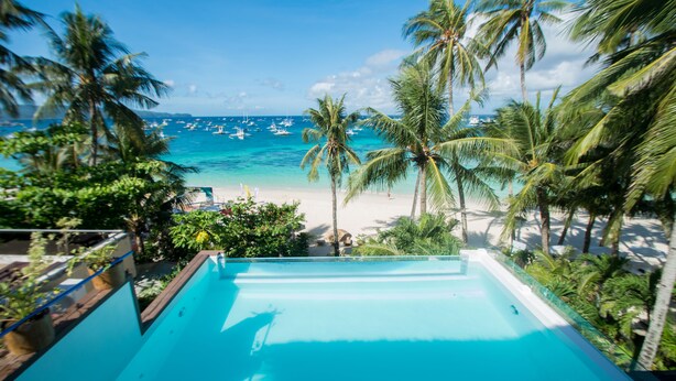 A pool with a view of a beach and palm trees. - Signature Boracay Blue (Boracay Island)
