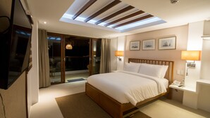 A modern hotel bedroom with a large bed, skylight, sliding glass door to a balcony, and a bedside table with a lamp. - Signature Boracay Blue (Boracay Island)