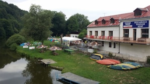 A riverside hotel with outdoor seating, tents, and canoes. - Hotel Ostende (Chocerady)