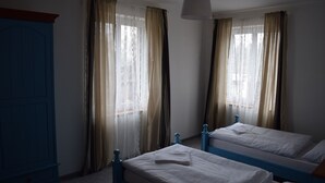 A room with two beds, a wardrobe, and a hanging light fixture. - Hotel Ostende (Chocerady)