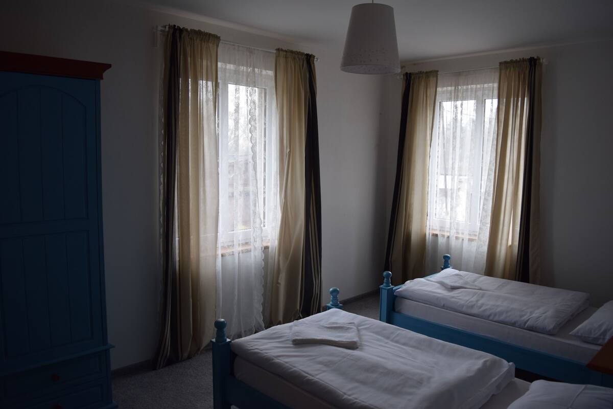 A room with two beds, a wardrobe, and a hanging light fixture.