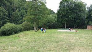 An outdoor area with a grassy field, trees, and a small structure. - Hotel Ostende (Chocerady)