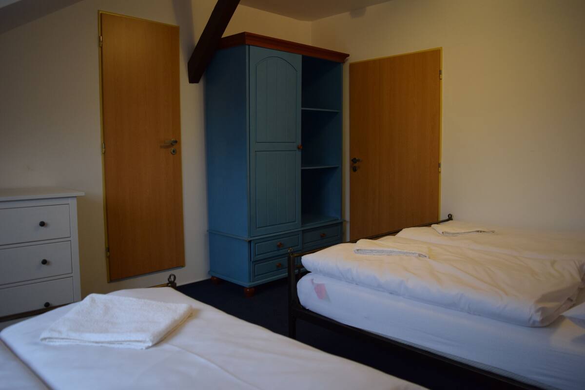 A bedroom with two beds, a wardrobe, and a dresser.