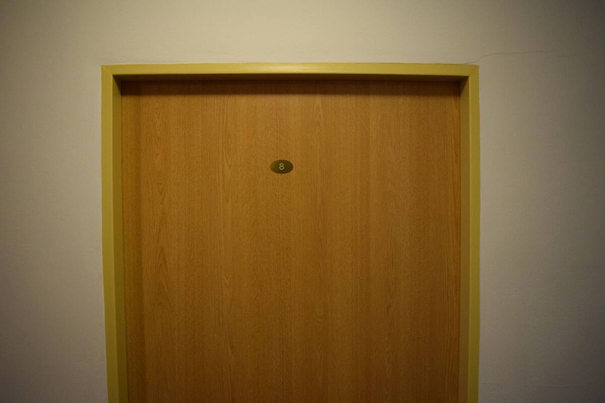 A wooden door with a yellow frame and a small number plate.