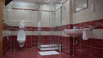 A modern bathroom with a glass-enclosed shower, a white toilet, and a sink with a mirror above it.