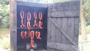 A wooden structure with a grill containing sausages. - Hotel Ostende (Chocerady)