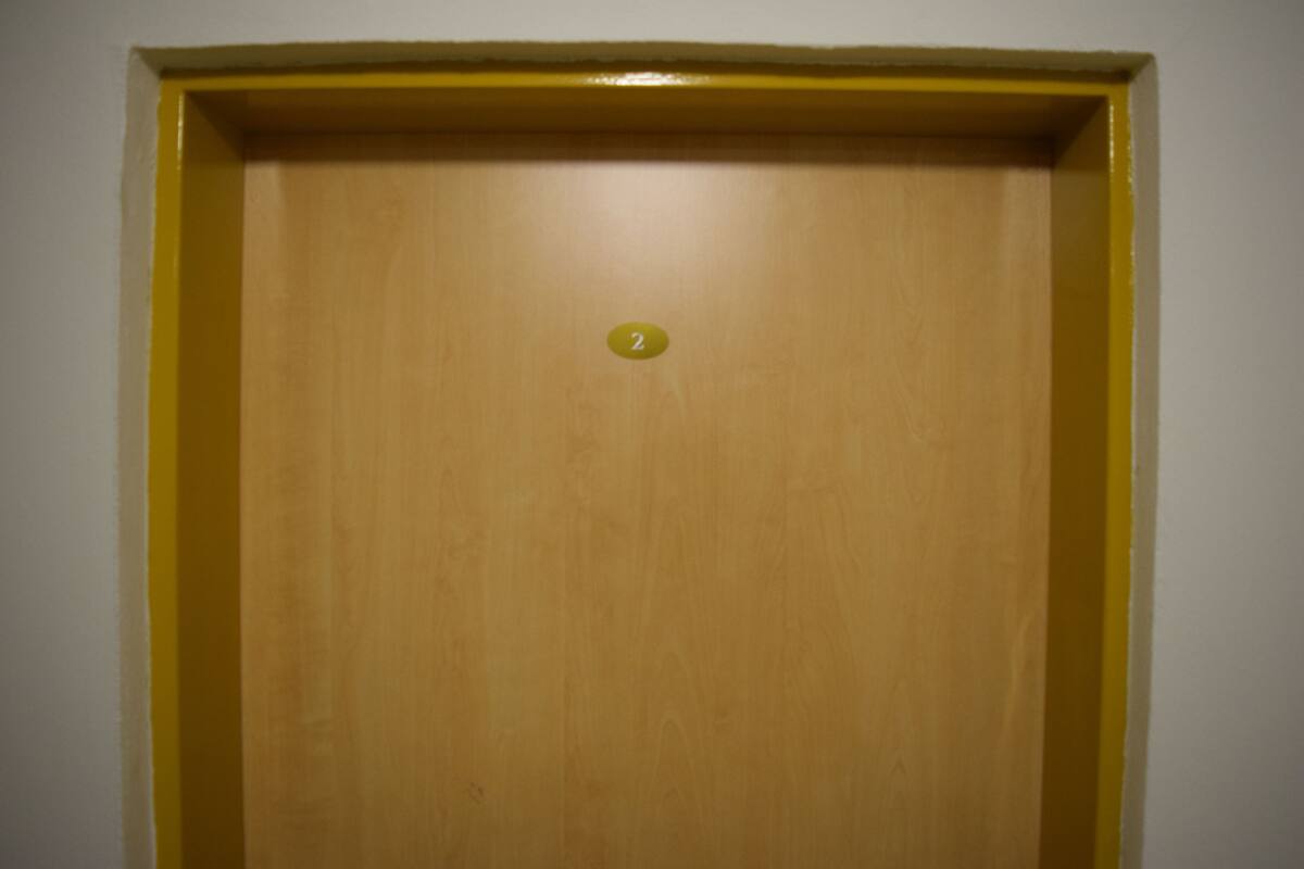 A wooden door with a yellow frame and a small number '2' on it.