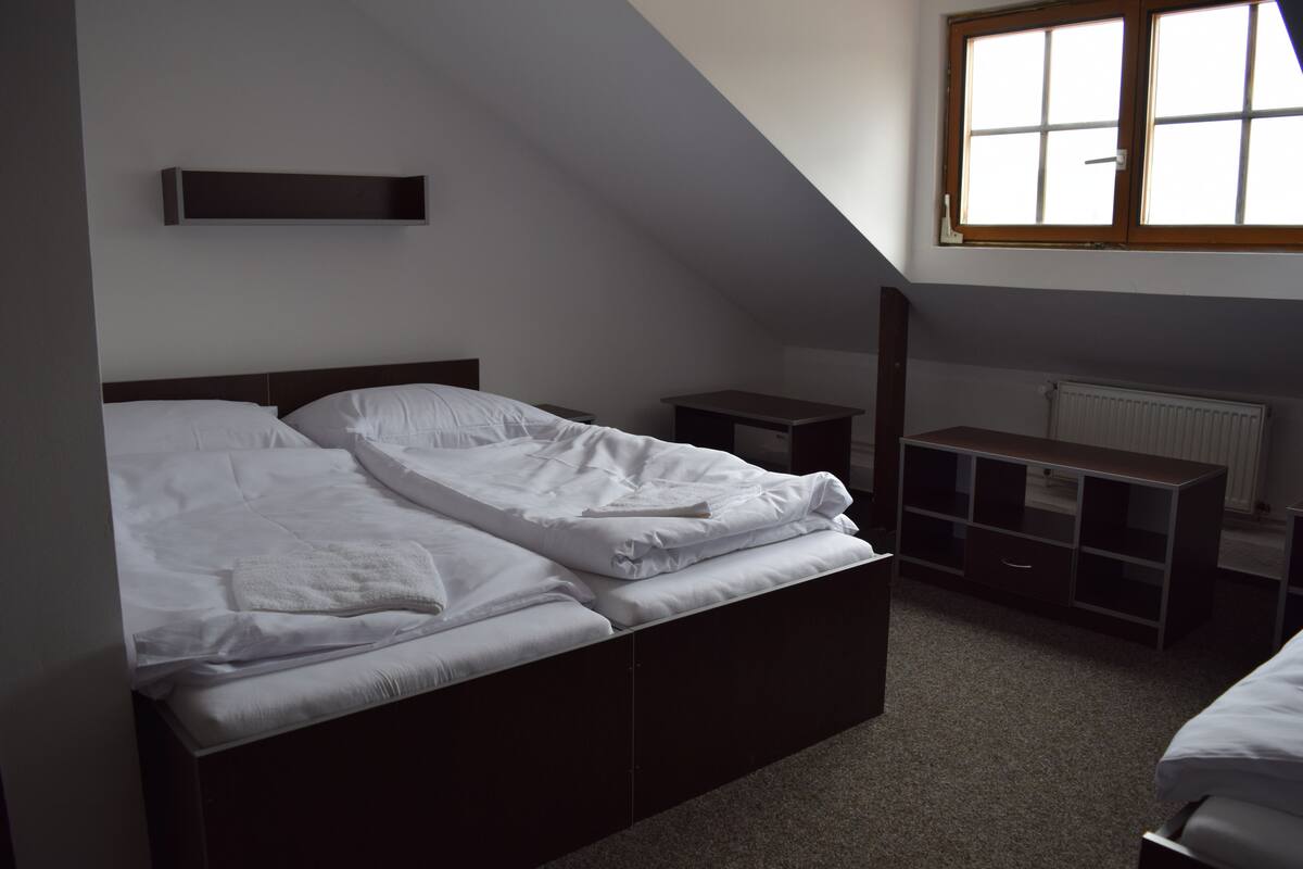 A bedroom with a bed, bedside table, and a window.