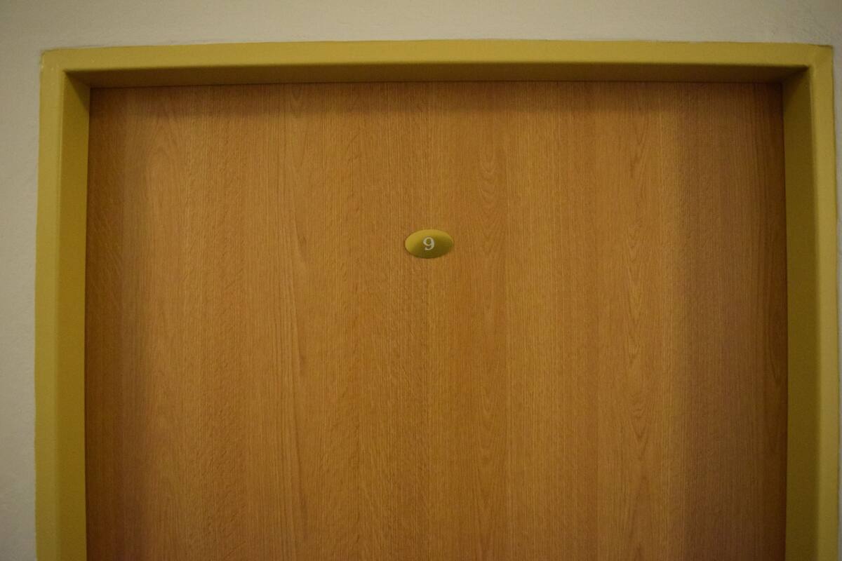 A wooden door with a yellow frame and a number 9 plaque.