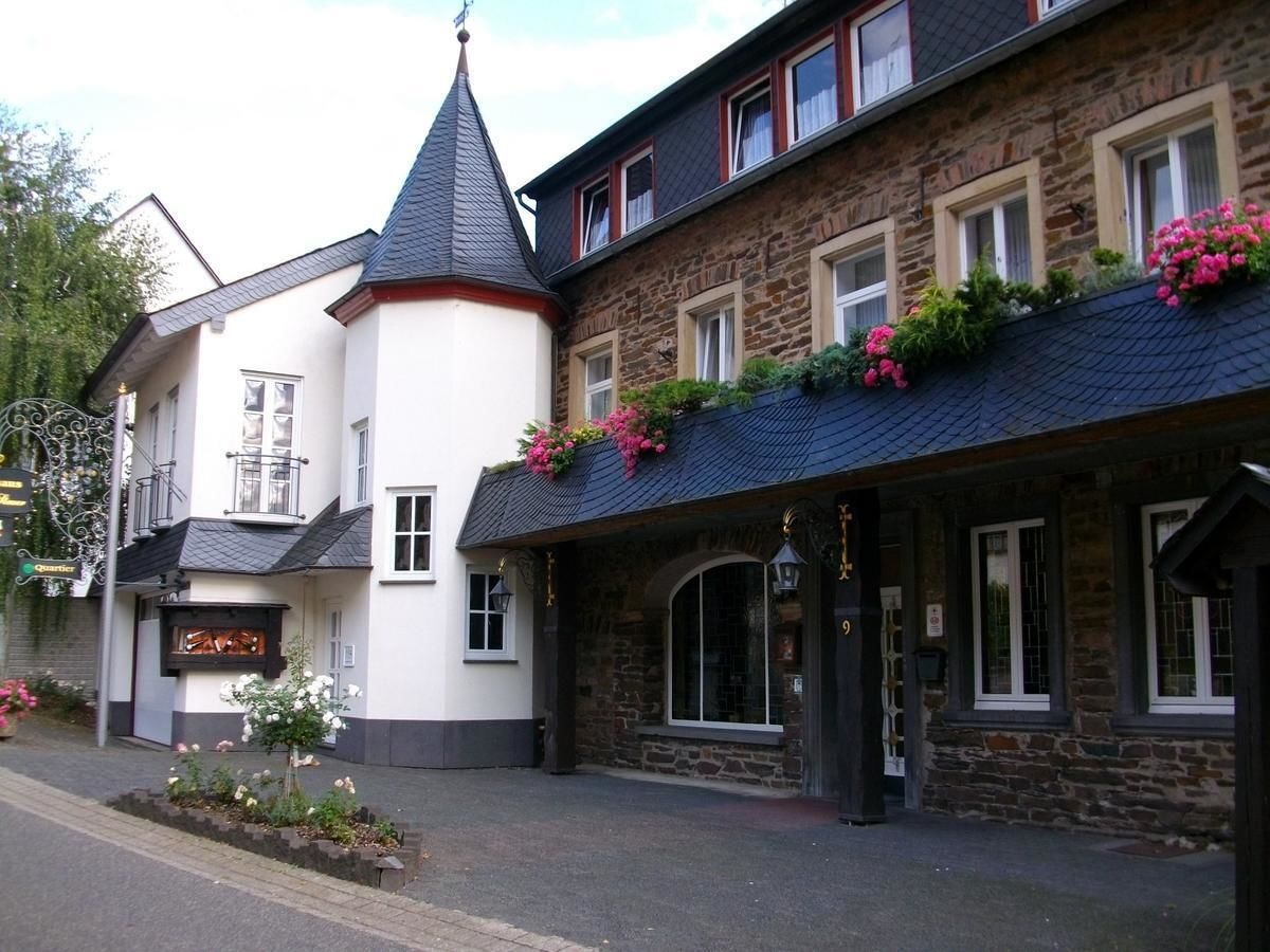A building with a stone facade, a black roof, and a small tower-like structure.