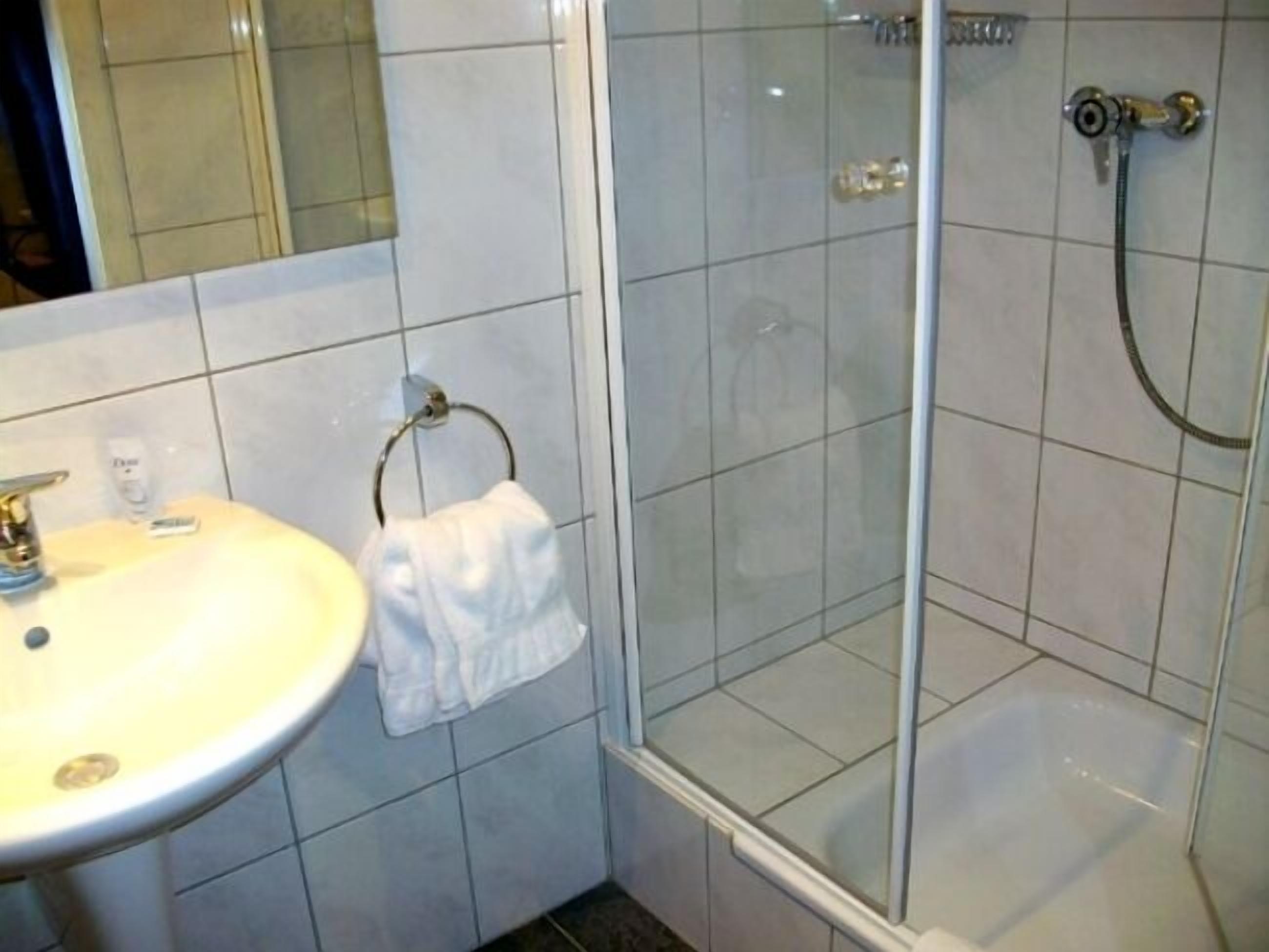 A bathroom with a sink, mirror, and glass shower enclosure.
