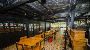 A restaurant with wooden tables and chairs, a patterned floor, and a bar area with stools. - Ngoc Son homestay (Ha Giang 1)