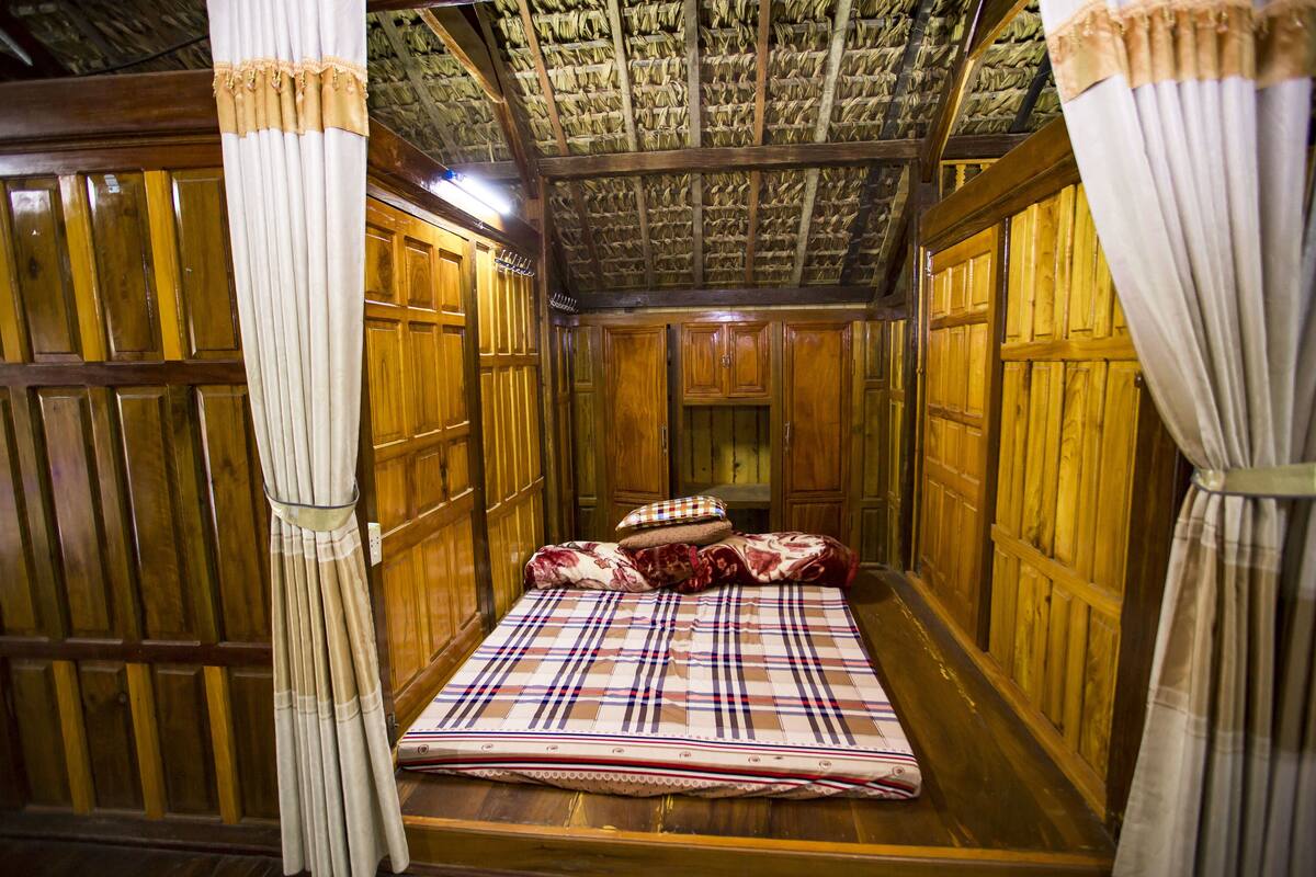 Une chambre traditionnelle en bois, avec un lit, des rideaux et un plafond orné d’un motif original.