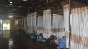 A room with wooden floors and curtains with a patterned border. There are several bags and suitcases on the floor. - Ngoc Son homestay (Ha Giang 1)