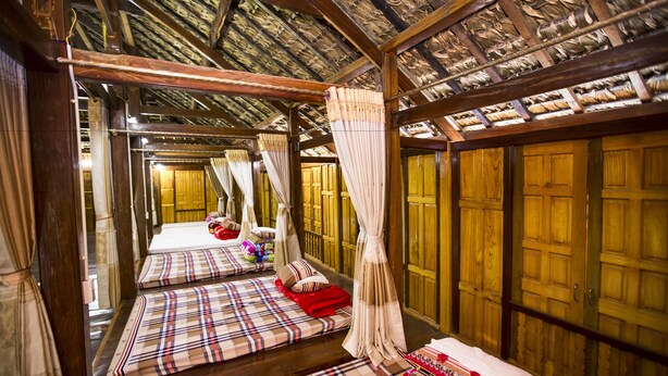 A traditional room with wooden beams, tatami mats, and a canopy bed. - Ngoc Son homestay (Ha Giang 1)