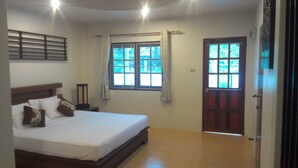 A bedroom with a bed, a window, a door, and a nightstand. - Surin House (Choeng Thale)