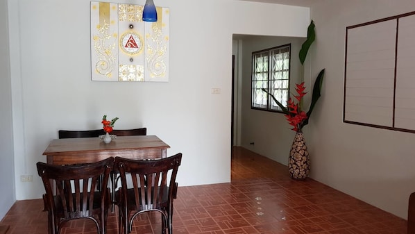 A dining area with a wooden table and chairs, a decorative wall piece, and a large plant.