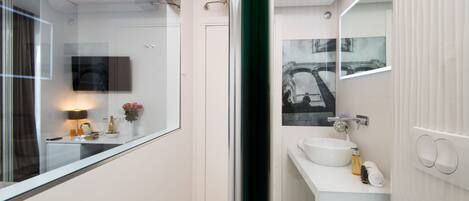 Un baño moderno con un espejo grande, un lavabo blanco y un piso de mármol.