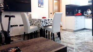 Um espaço de estar compacto com área de jantar, cozinha e TV fixada na parede.