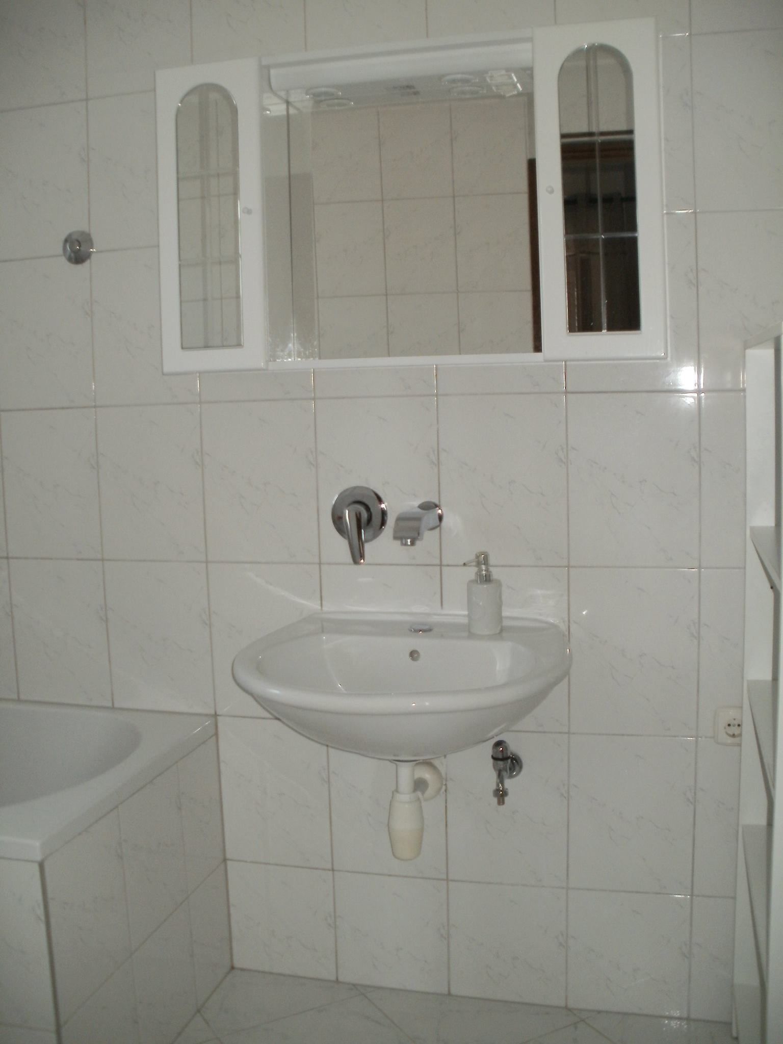 A bathroom with a white sink, mirror, and toilet.