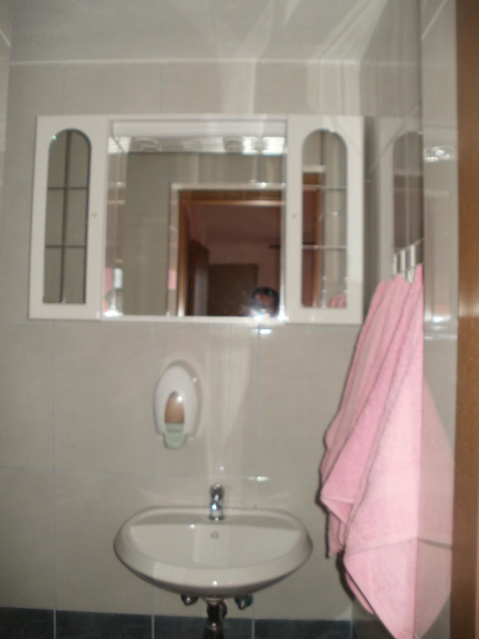 A bathroom with a sink, a mirror, and a towel hanging on the wall.