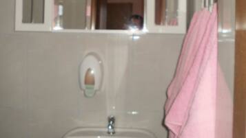 A bathroom with a sink, a mirror, and a towel hanging on the wall.