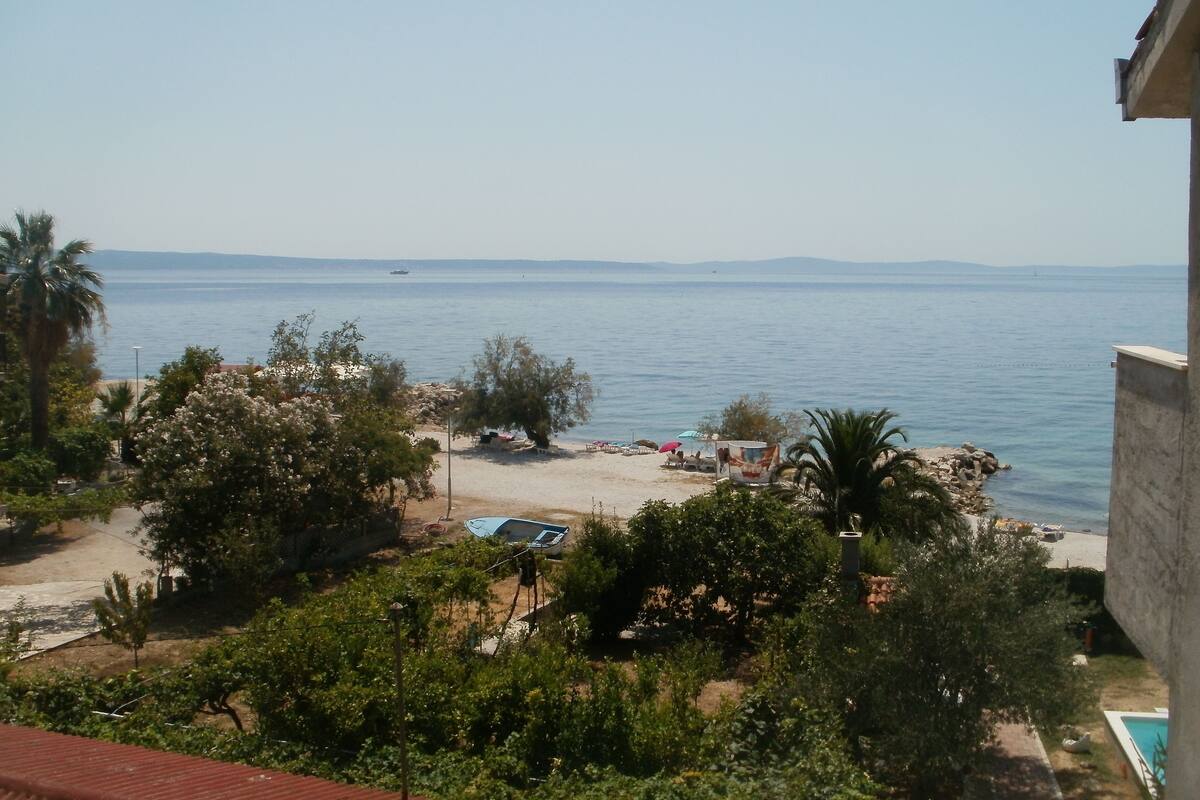 A coastal view with a beach, palm trees, and a clear sky.