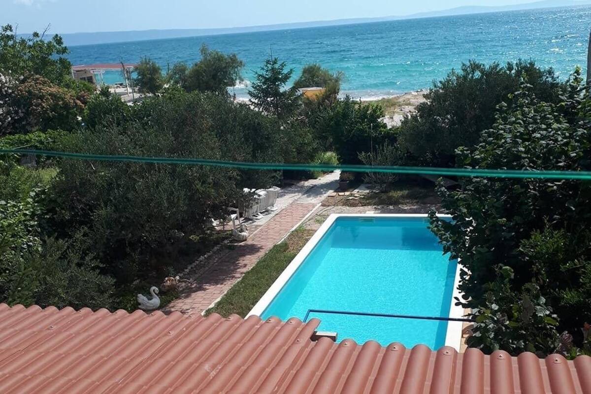 A rooftop terrace with a swimming pool, overlooking a beach and the sea.