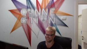 A person seated in front of a wall with a colorful geometric design and the word "CONNECTION" prominently displayed. - German Colony Guest House (Haifa)