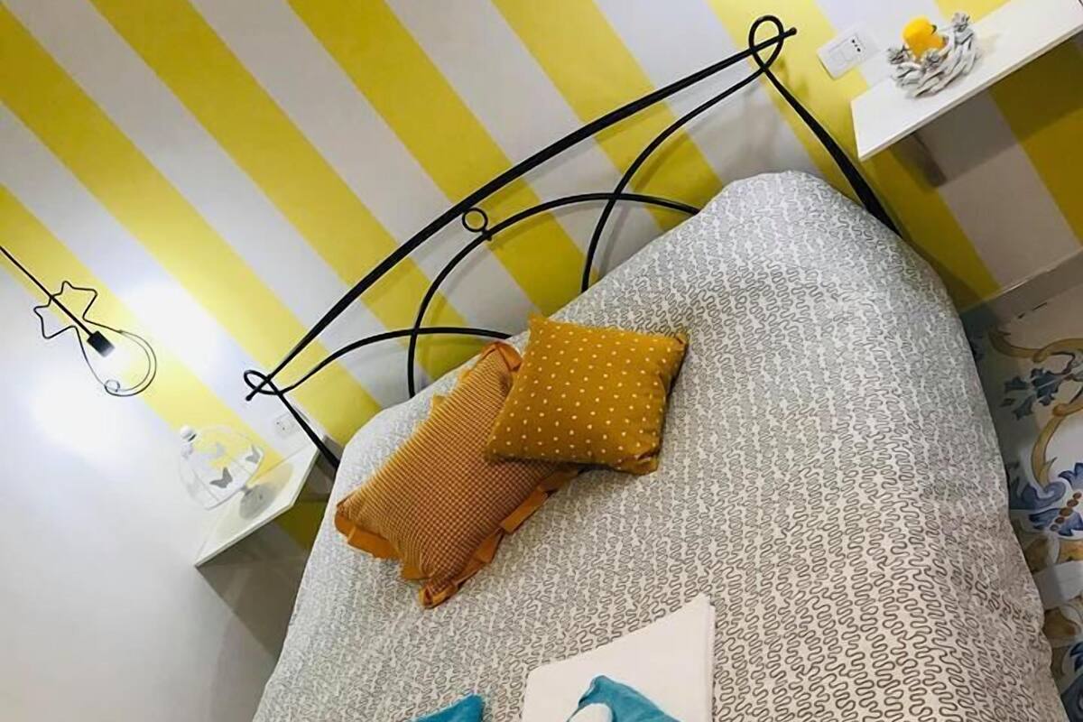 Cama com cabeceira estampada, duas almofadas e toalhas dobradas.
