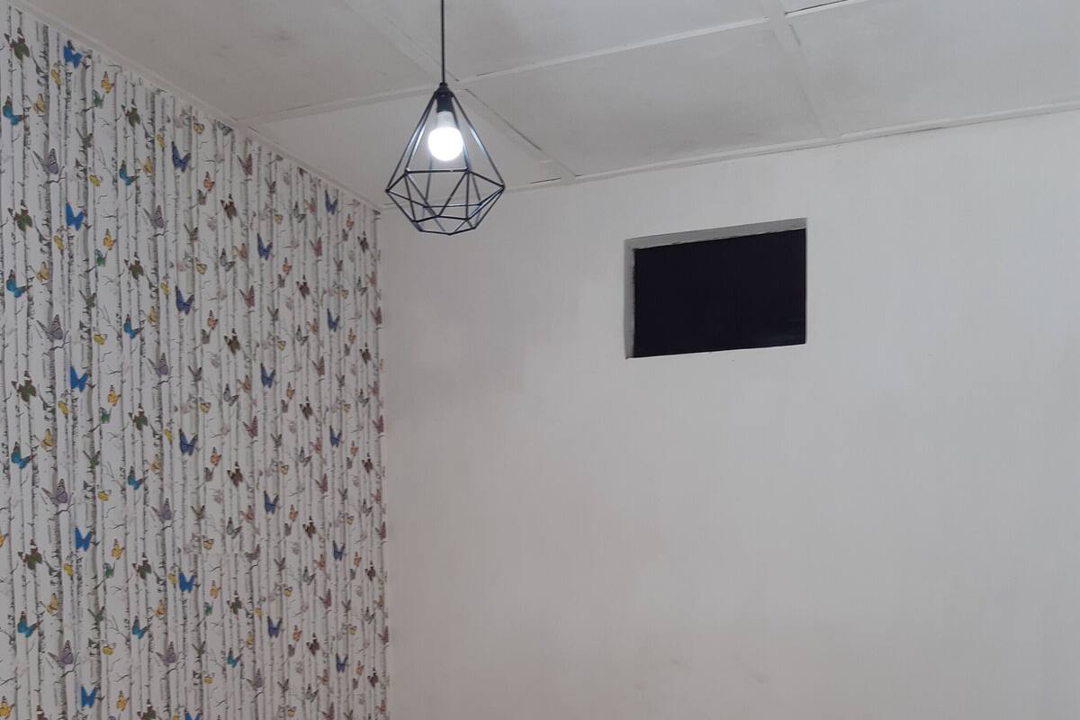 A room with a bed, a small window, and a patterned curtain.