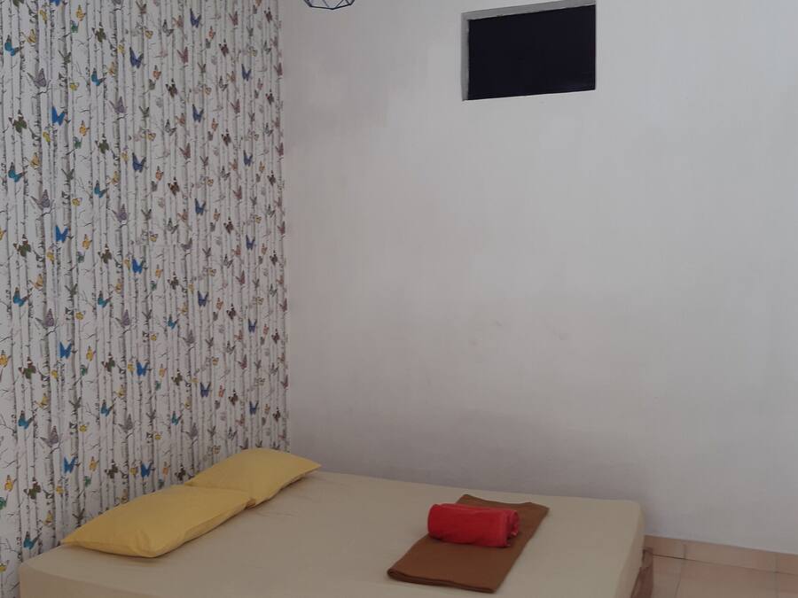 A room with a bed, a small window, and a patterned curtain.