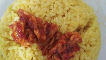 Un plato de arroz amarillo con una porción de salsa roja por encima.