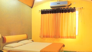 A hotel room with a bed, a bedside table, a nightstand, an air conditioning unit, and a window with curtains. - Hotel Greenpark (Danta)