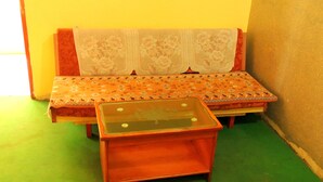 A small room with a sofa and a wooden table with a glass top. - Hotel Greenpark (Danta)
