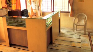 A reception desk labeled "Hotel Green Park" with a check-out sign, a plastic chair, and a window with curtains. - Hotel Greenpark (Danta)