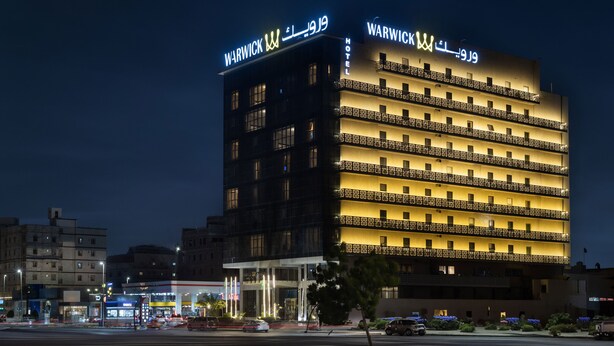 Een hotel met meerdere verdiepingen, verlichte reclameborden en balkons.