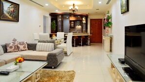 Uma sala de estar moderna com sofá, mesa de centro, televisão e um espaço de jantar com cadeiras e mesa.