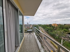 A balcony with a view of a cityscape, including buildings and greenery.