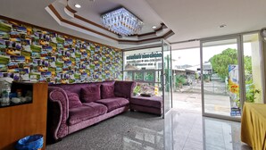A reception area with a purple sofa, a wall decorated with photos, and a glass door leading outside. - Baan Pattamaporn Hotel (Hua Hin)