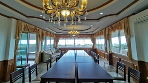 A spacious conference room with a large table, comfortable seating, and a decorative chandelier. - Baan Pattamaporn Hotel (Hua Hin)