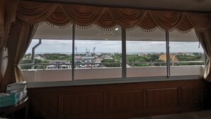 A room with a large window overlooking a cityscape, including buildings and greenery. - Baan Pattamaporn Hotel (Hua Hin)